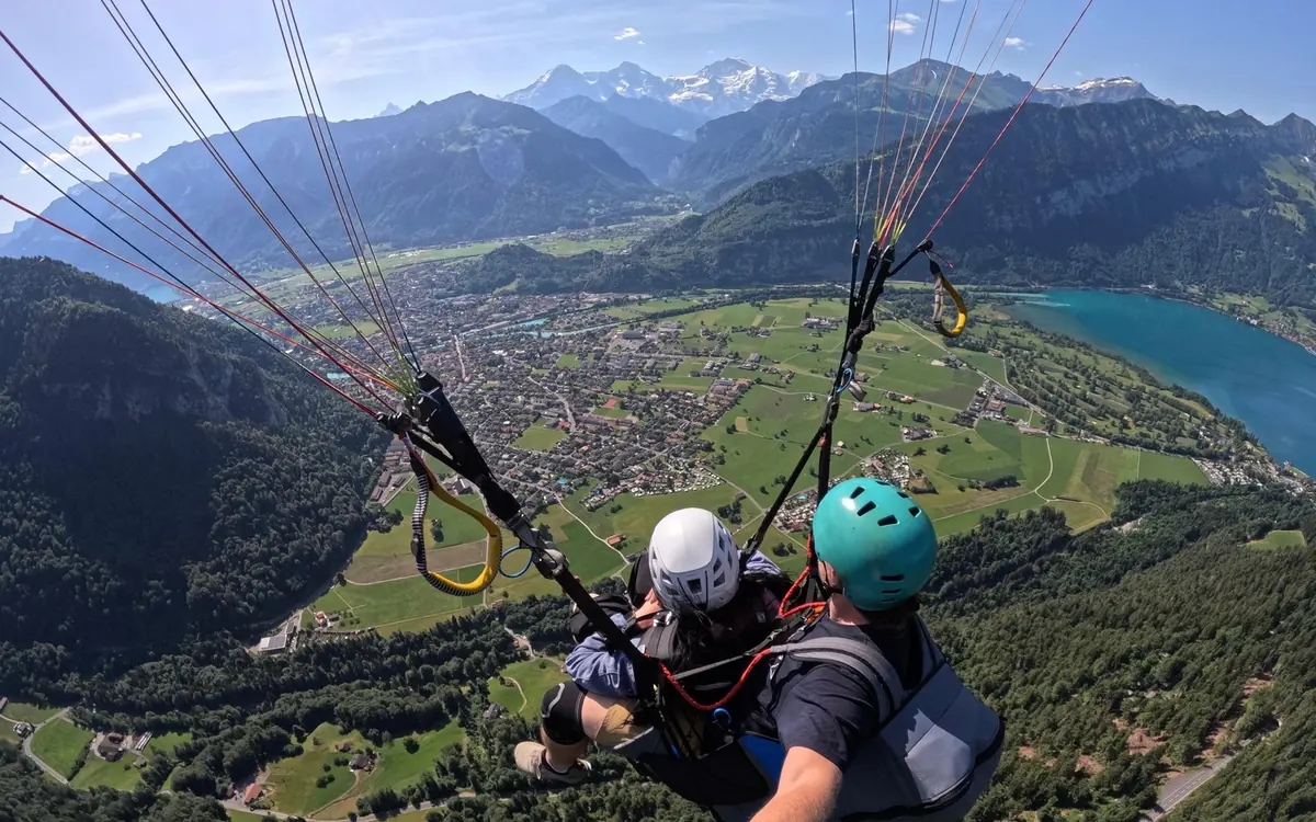 A tandem paraglider above Interlaken with the two lakes below